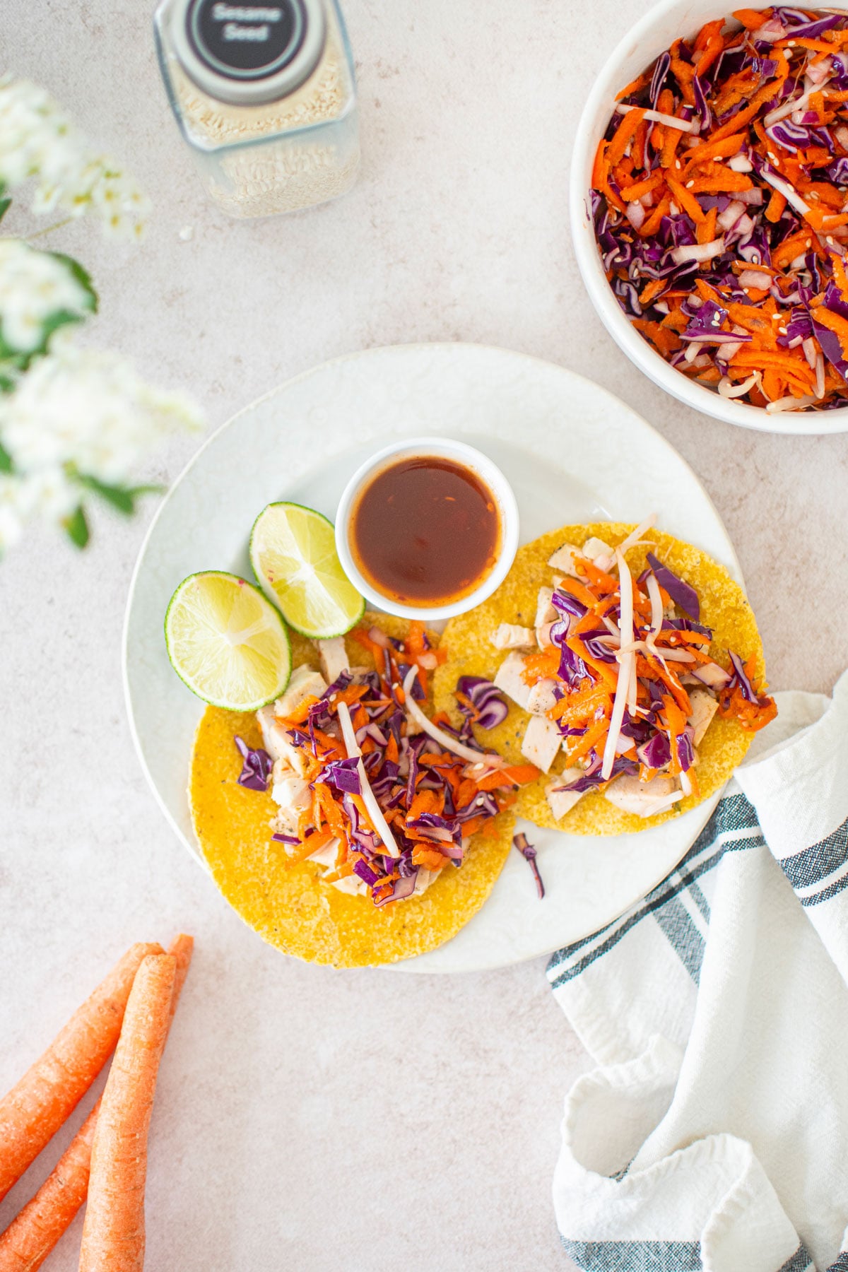 sweet chili chicken soft tacos being assembled on a white plate with lime.
