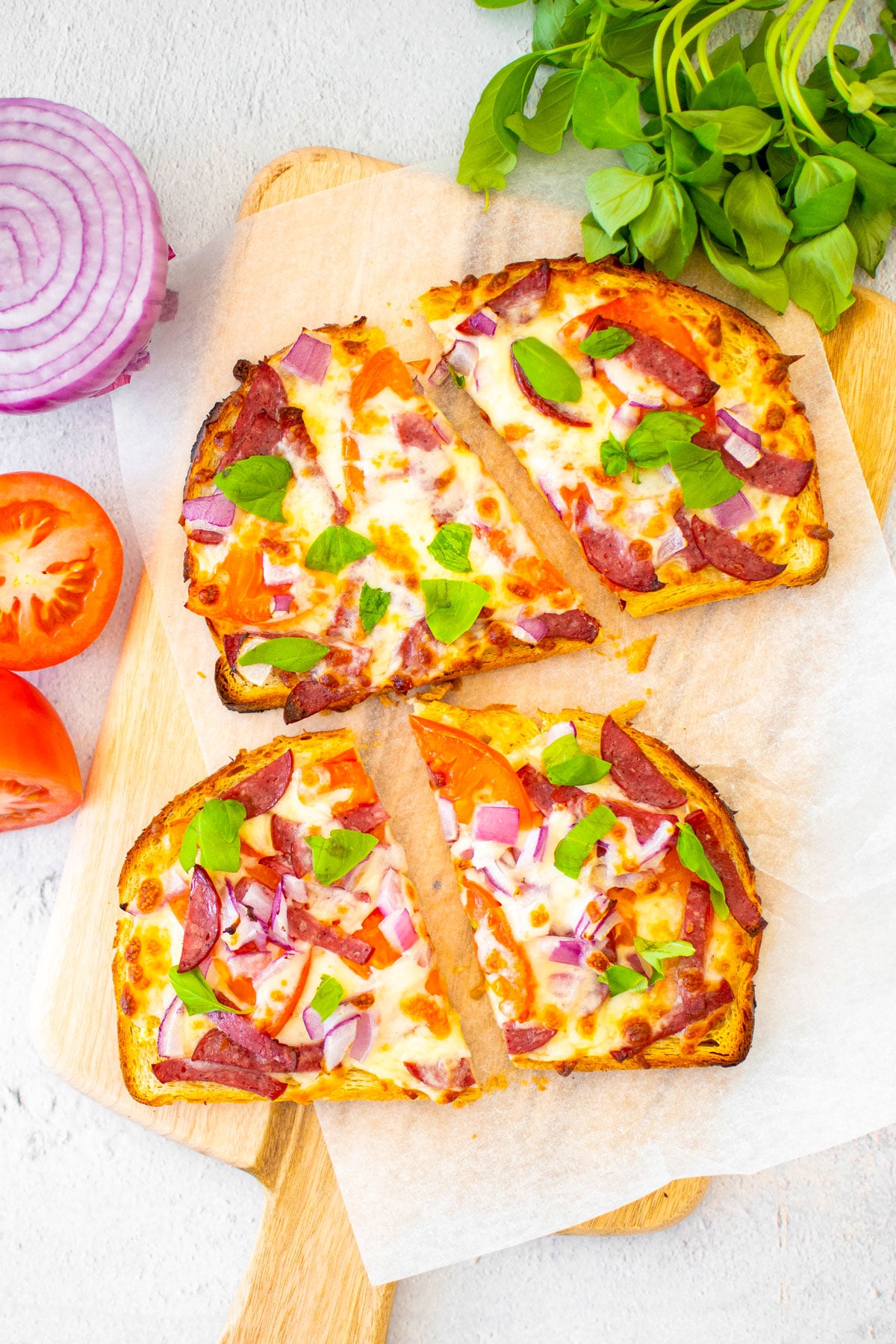 air fryer loaded garlic bread slices cut in half on a wood cutting board.