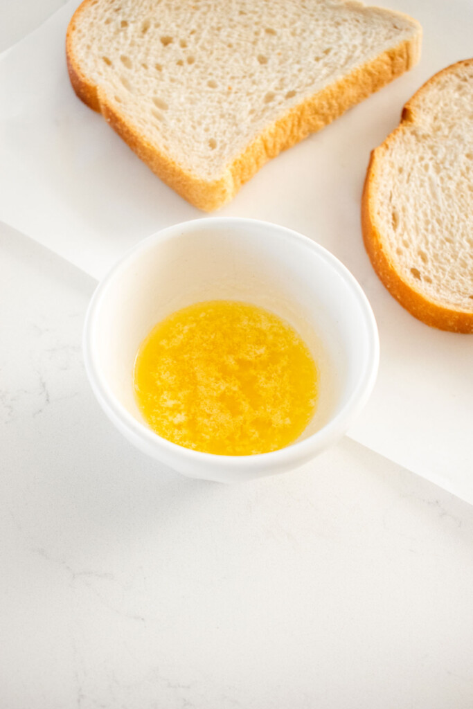 small bowl of melted butter and garlic on a marble counter.