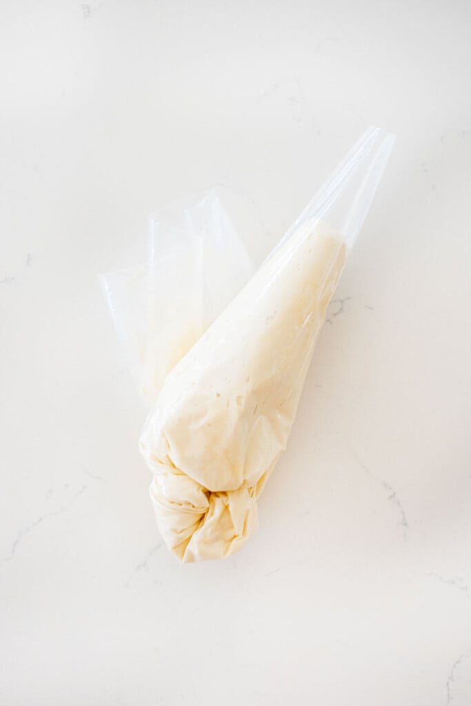 piping bag with buttercream frosting on a white marble counter.