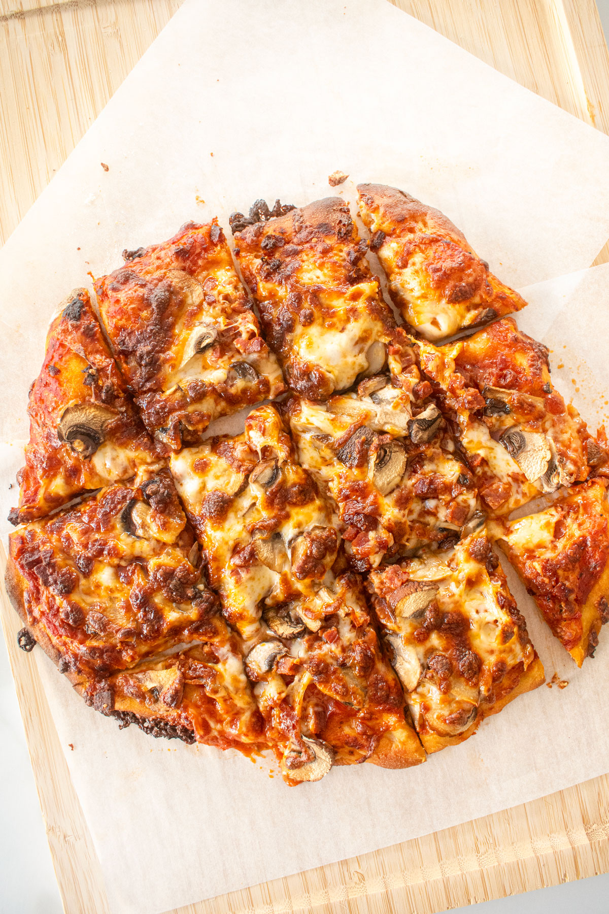chicago style thin crust pizza on a wood cutting board cut into square slices.