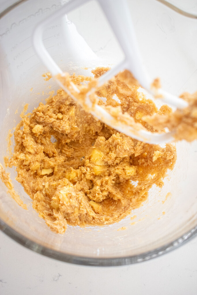 creamed coconut oil and sugar and butter in a glass mixing bowl on a marble counter.