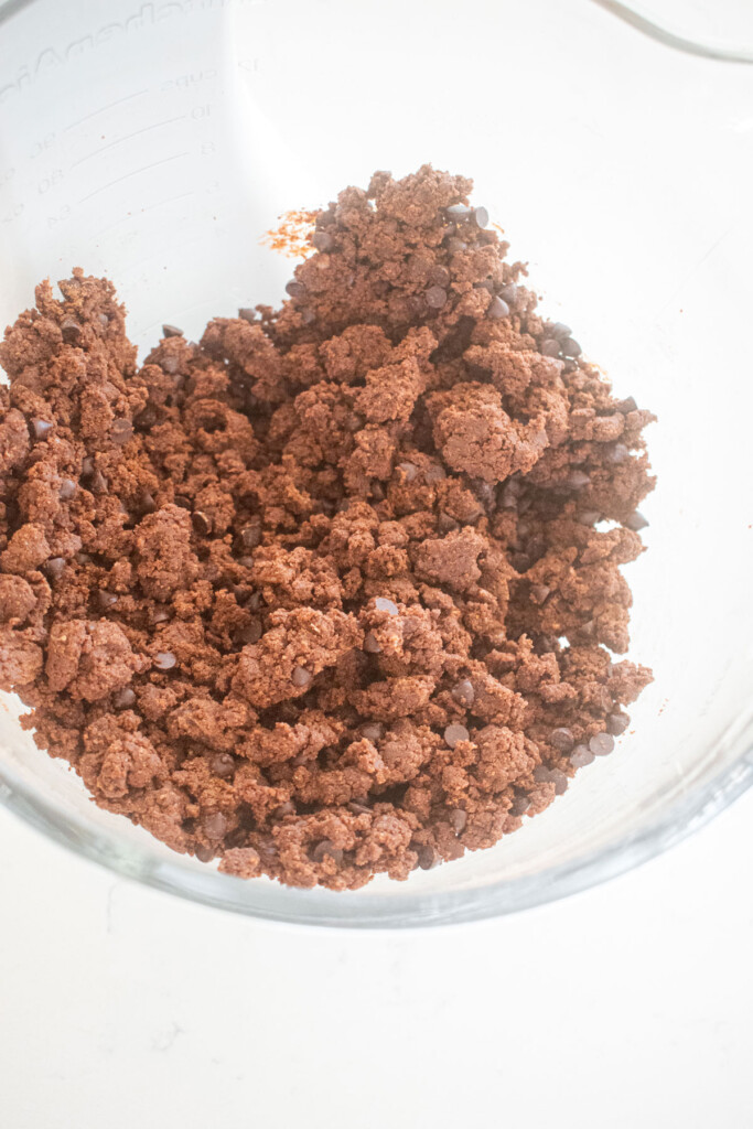 chocolate sea salt cookie dough in a glass mixing bowl on a marble counter.