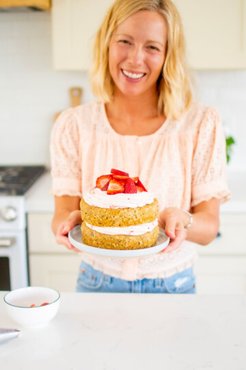 woman holding a strawberry naked cake in the kitchen.