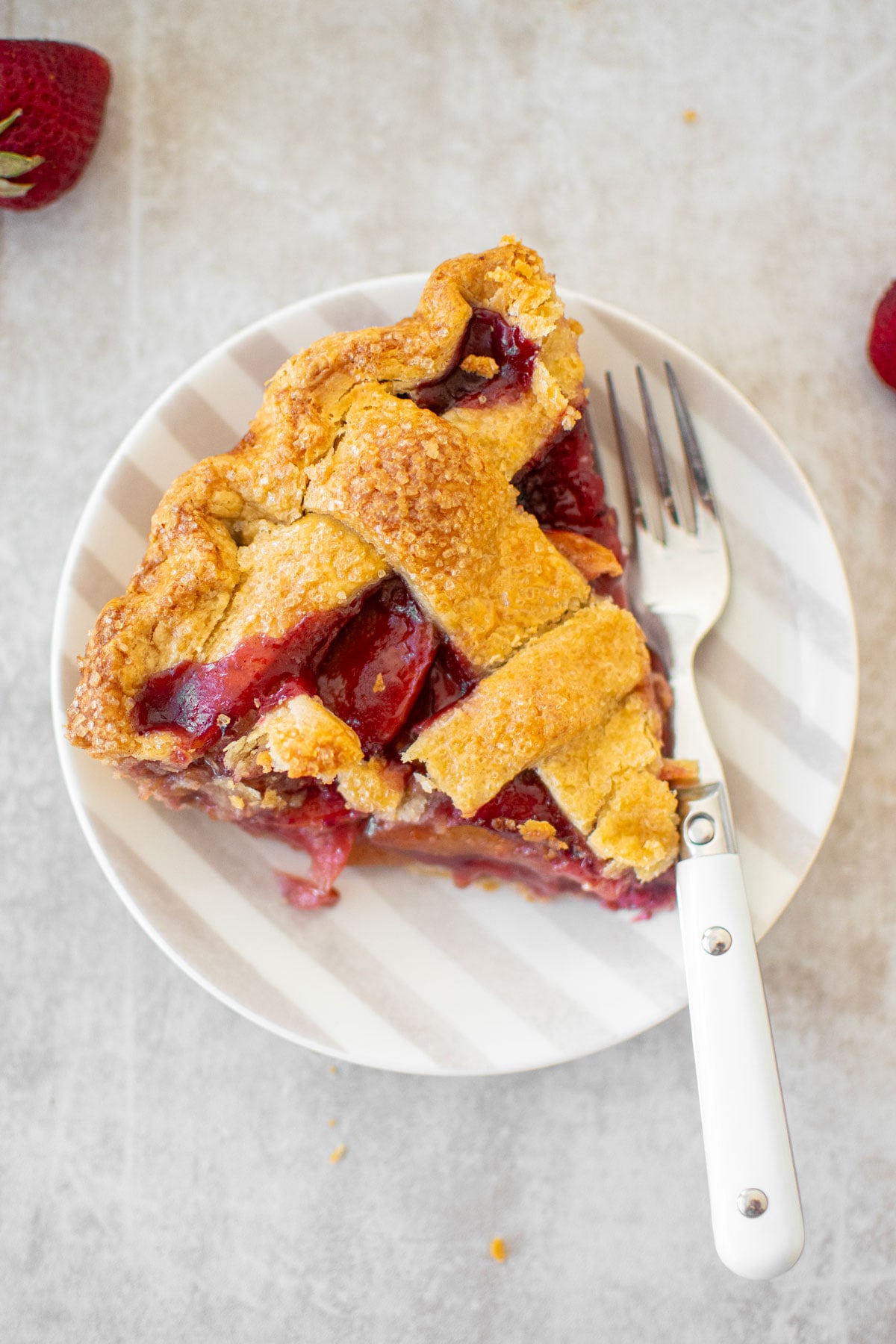 apple berry pie slice on a plate with a fork.