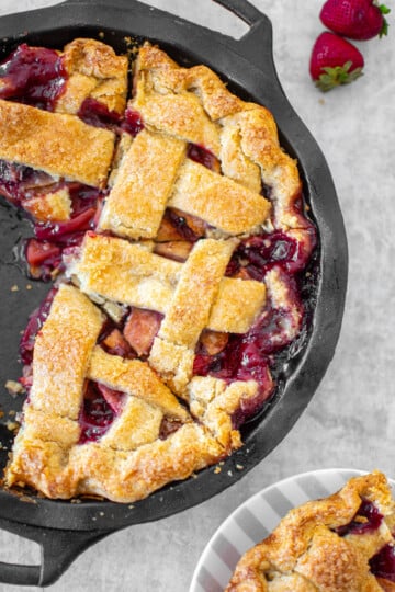 apple berry pie in a cast iron pie pan cut into slices.