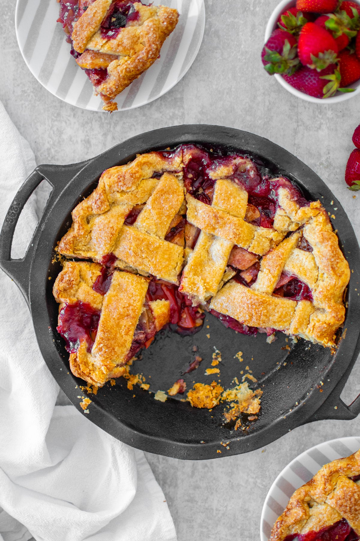apple berry pie in a cast iron pie pan, cut into slices.