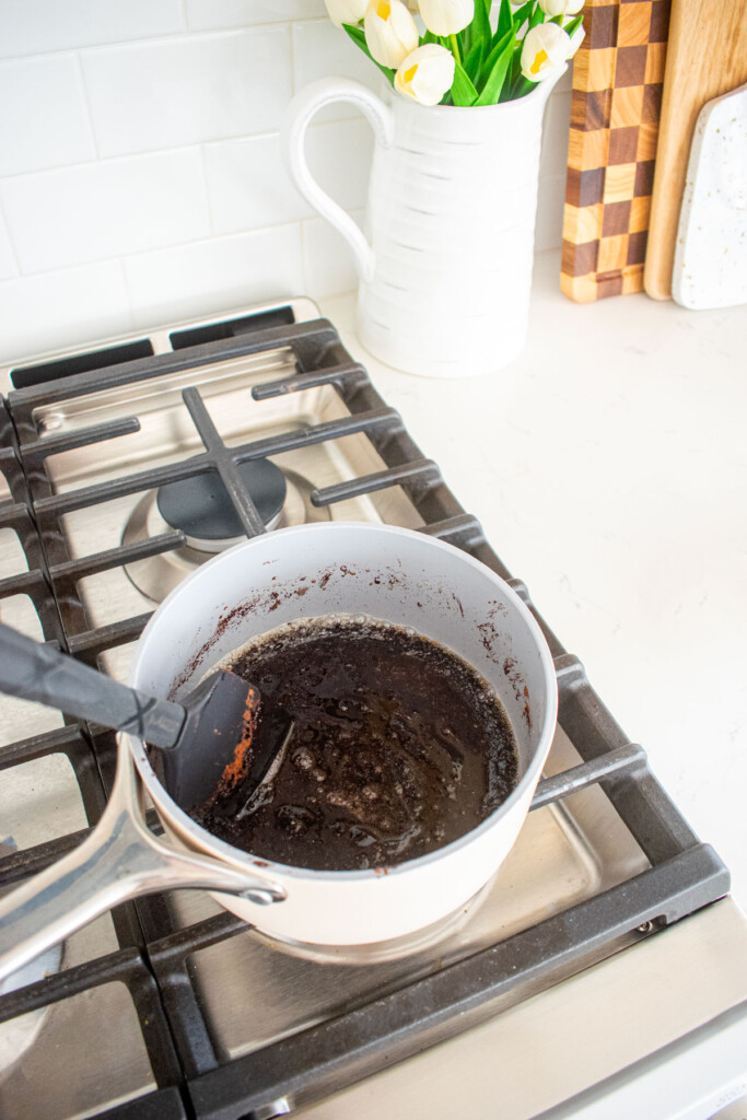 chocolate bourbon pecan pie filling being cooked in a small pot on the stovetop.