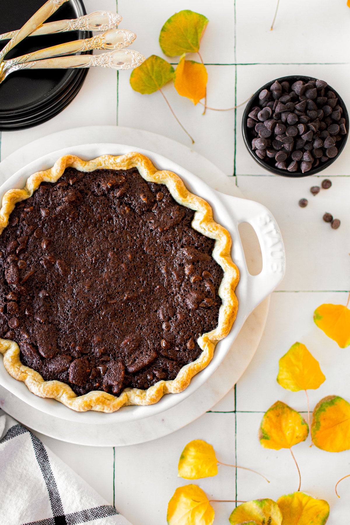 chocolate bourbon pecan pie in a white pie dish on a white tile countertop.