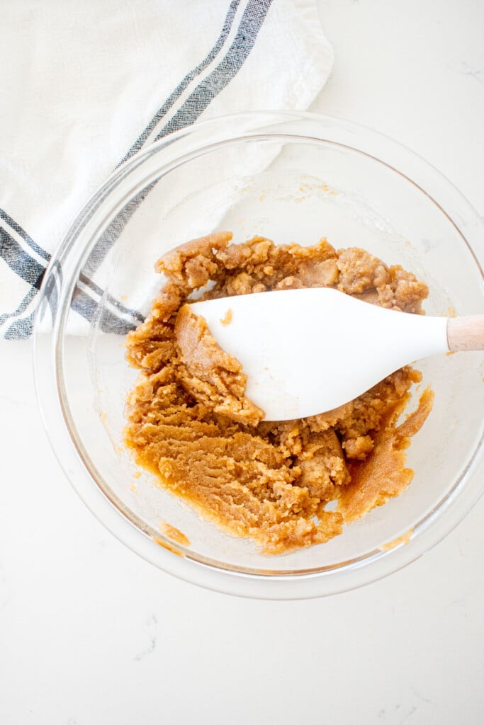 crumb topping mixed together in a mixing bowl for dutch apple pie on a marble counter.