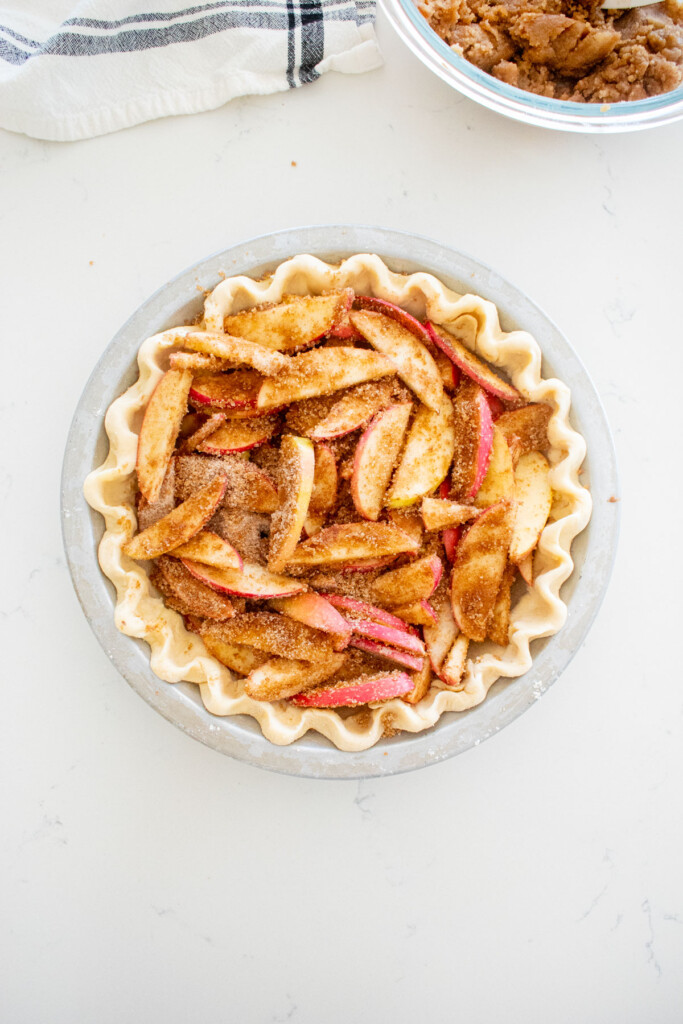 pie crust with apple pie filling in it on a marble counter.