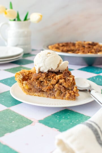 dutch apple pie slice on a plate with a scoop of vanilla ice cream on top.