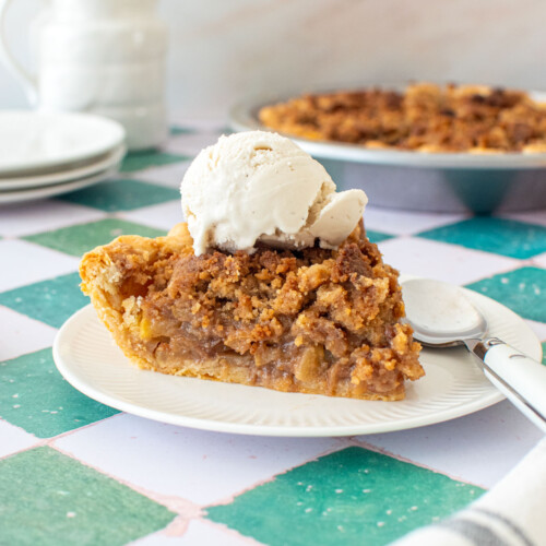 dutch apple pie slice on a plate with a scoop of vanilla ice cream on top.