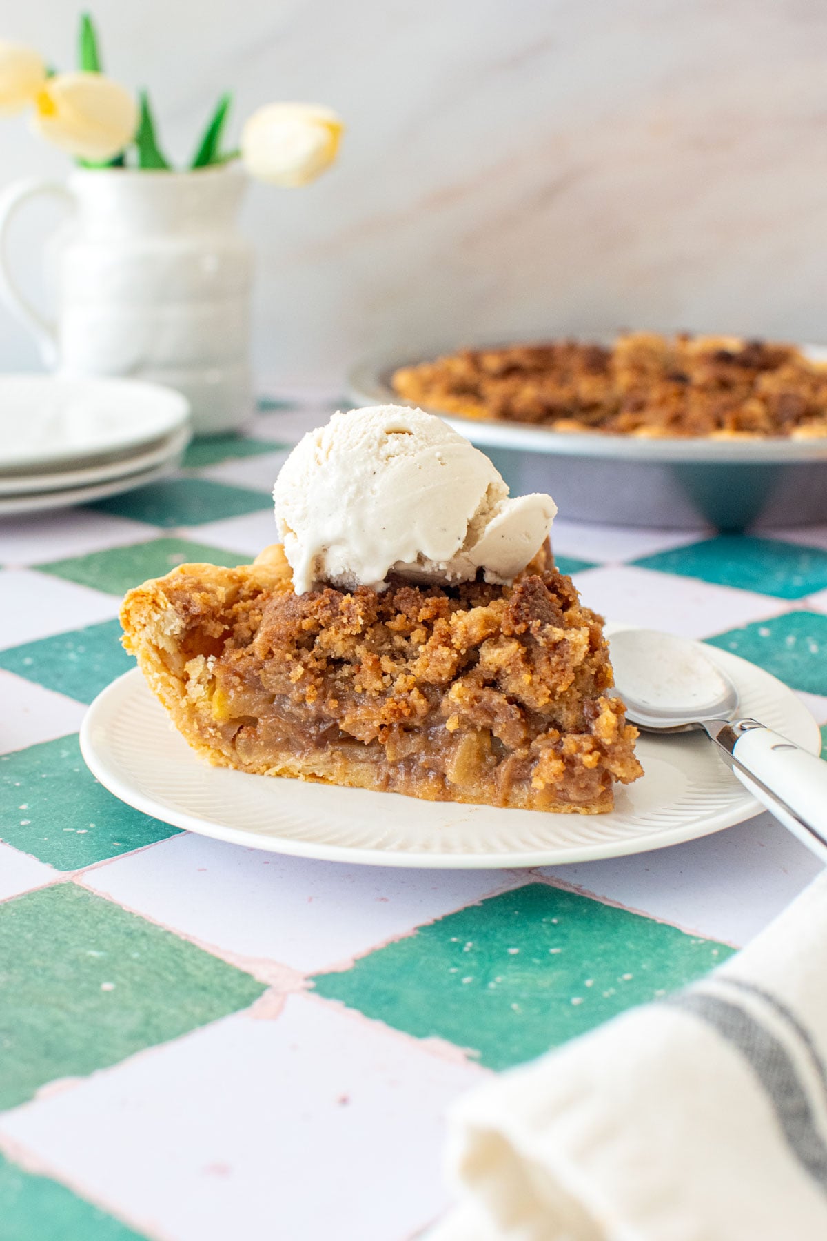 dutch apple pie slice on a plate with a scoop of vanilla ice cream on top.
