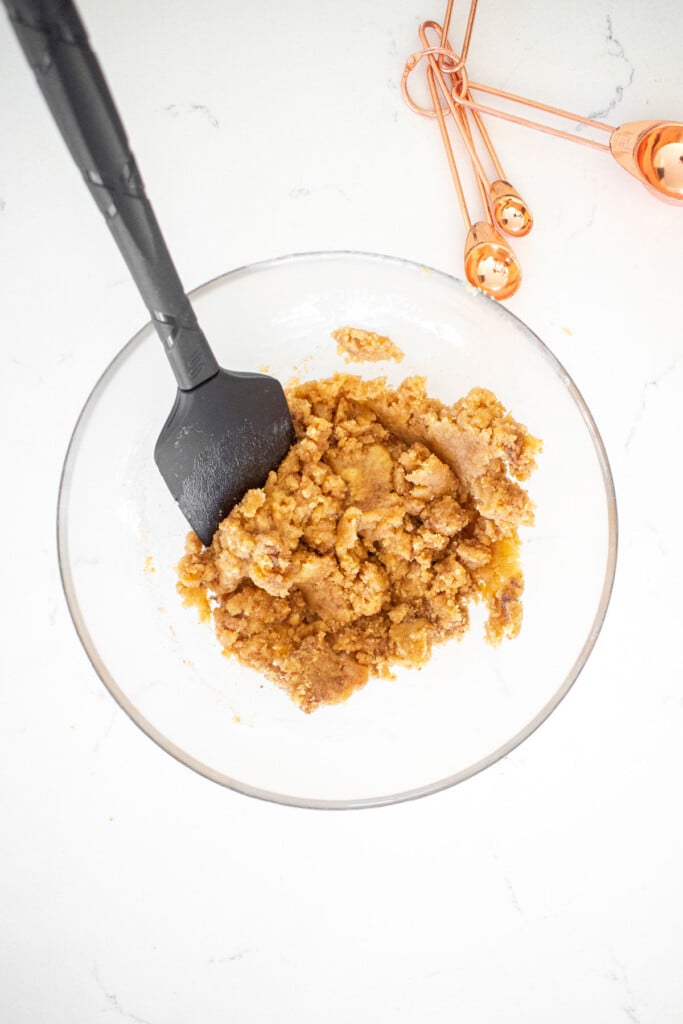 streusel topping in a glass mixing bowl on a white marble counter.