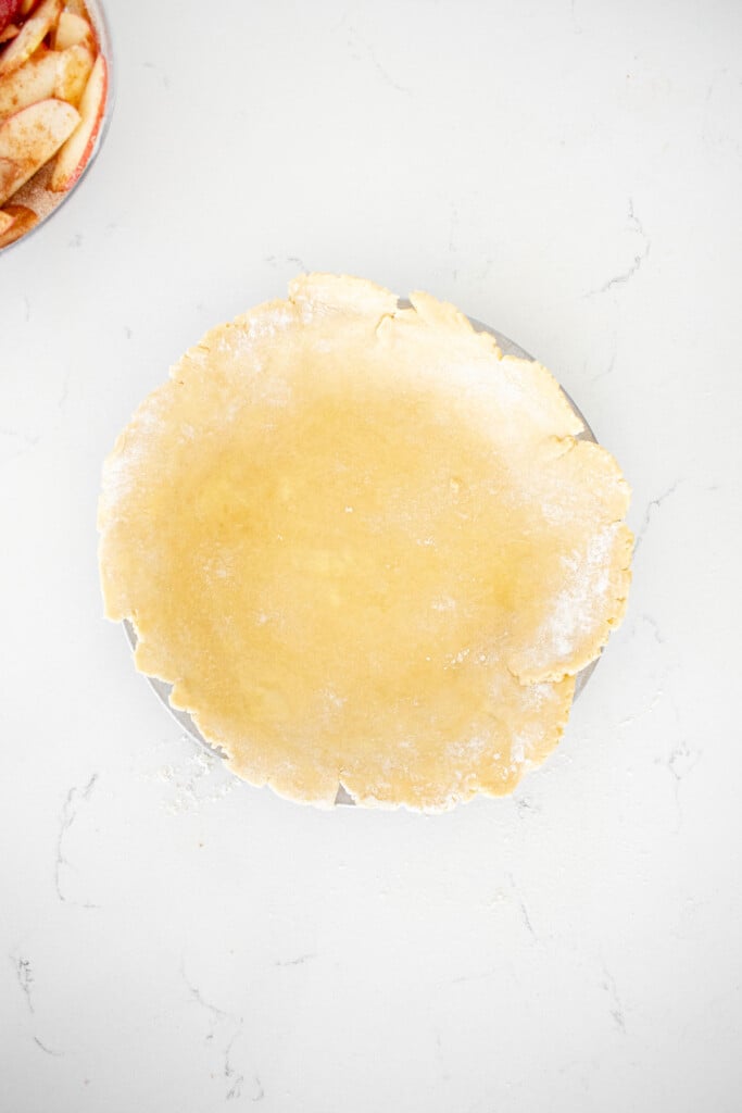 pie crust placed on top of a pie pan on a white marble counter.