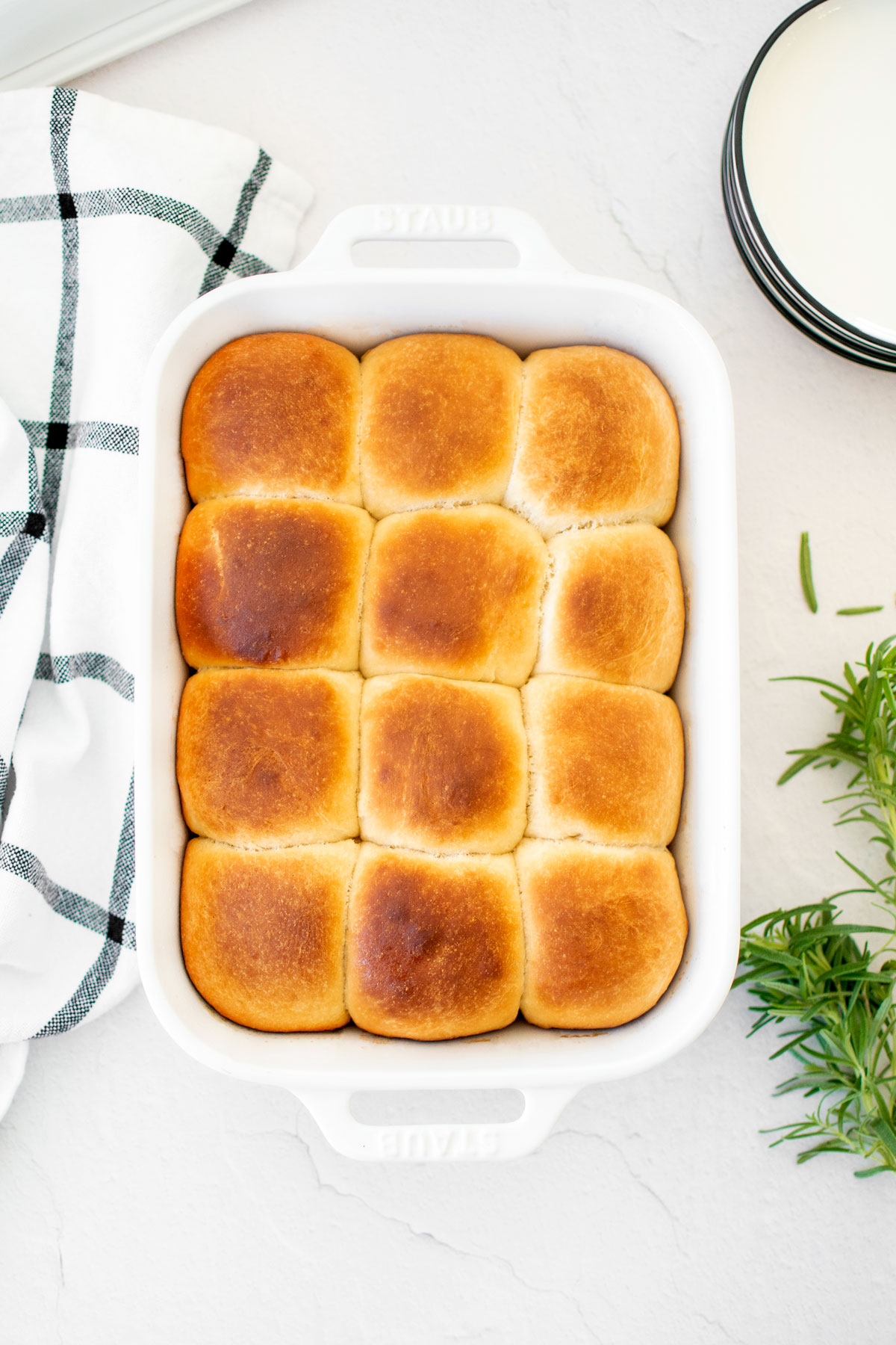 white ceramic dish of honey butter dinner rolls on the dinner table.