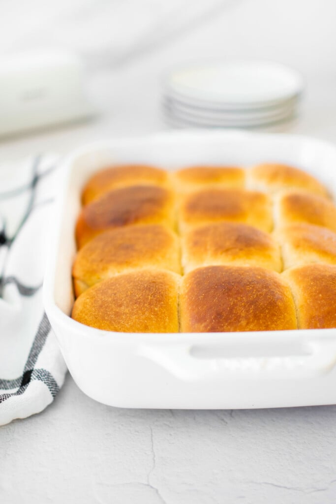 white ceramic dish of honey butter dinner rolls on the dinner table.