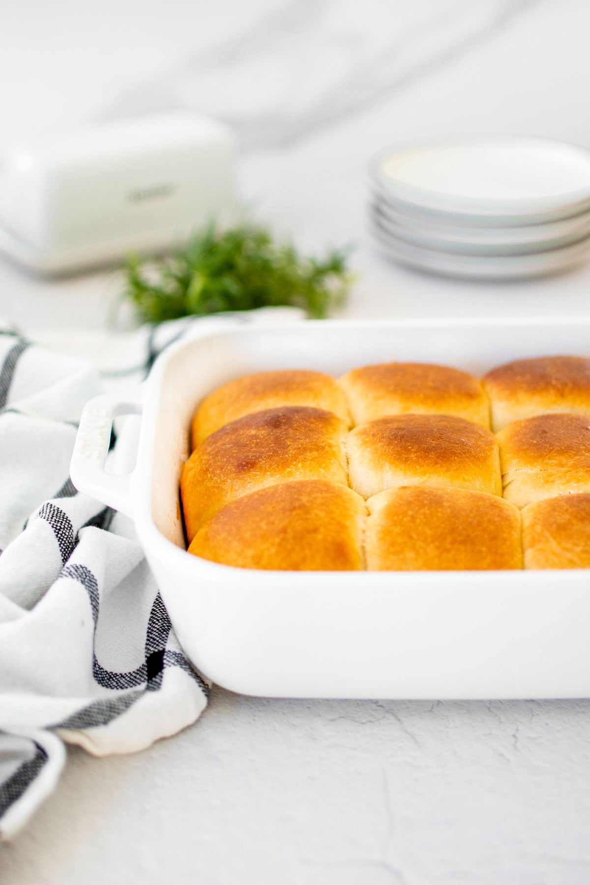 white ceramic dish of honey butter dinner rolls on the dinner table.
