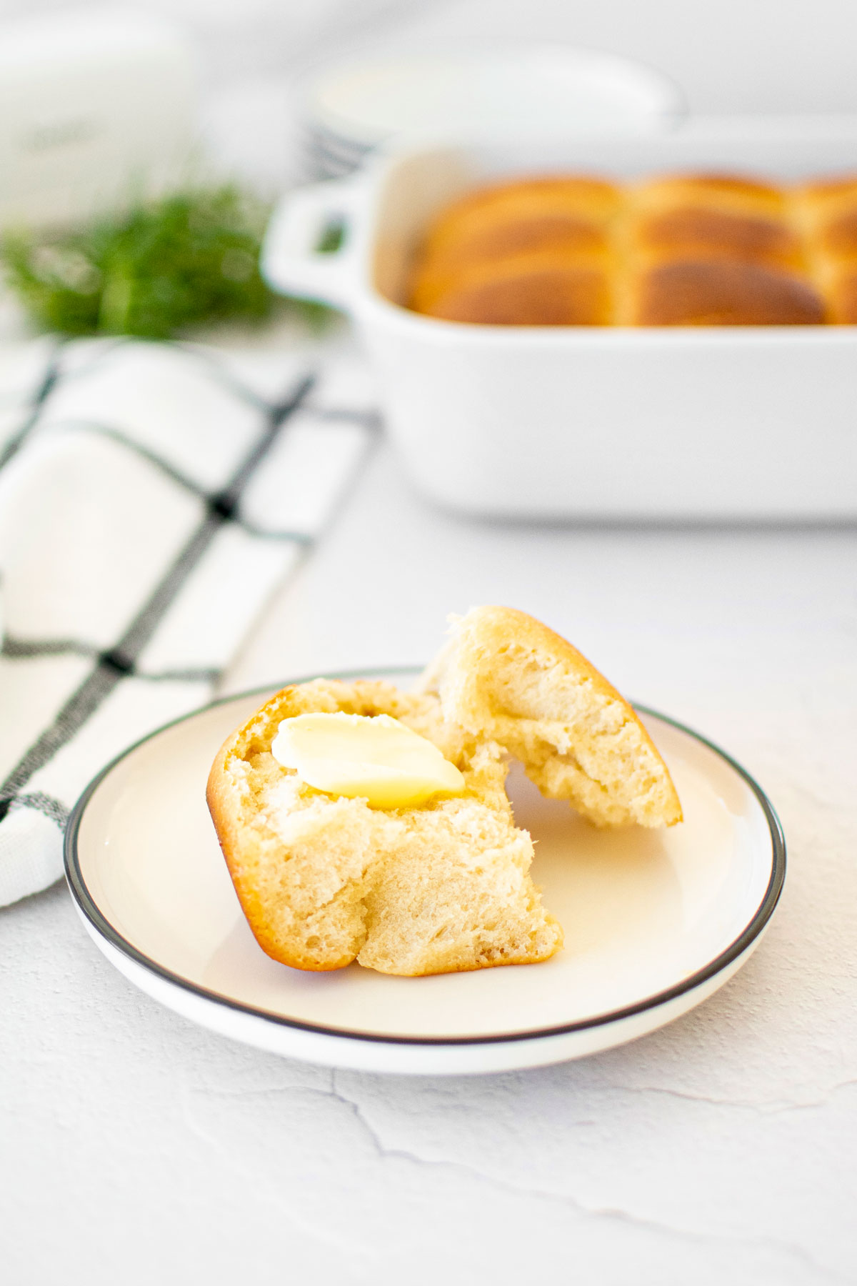 honey butter dinner roll broke in half with butter on a small white plate.