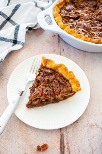 slice of honey pecan pie on a plate on a wood table.
