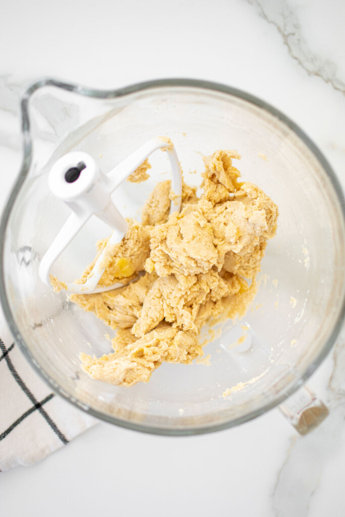 pie dough mixed together in the bowl of a mixer on a white countertop.