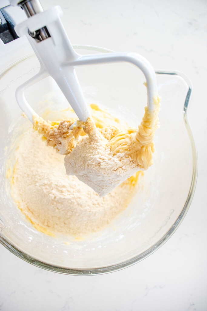 ingredients for shortbread cookies in a glass mixing bowl on a white marble counter.