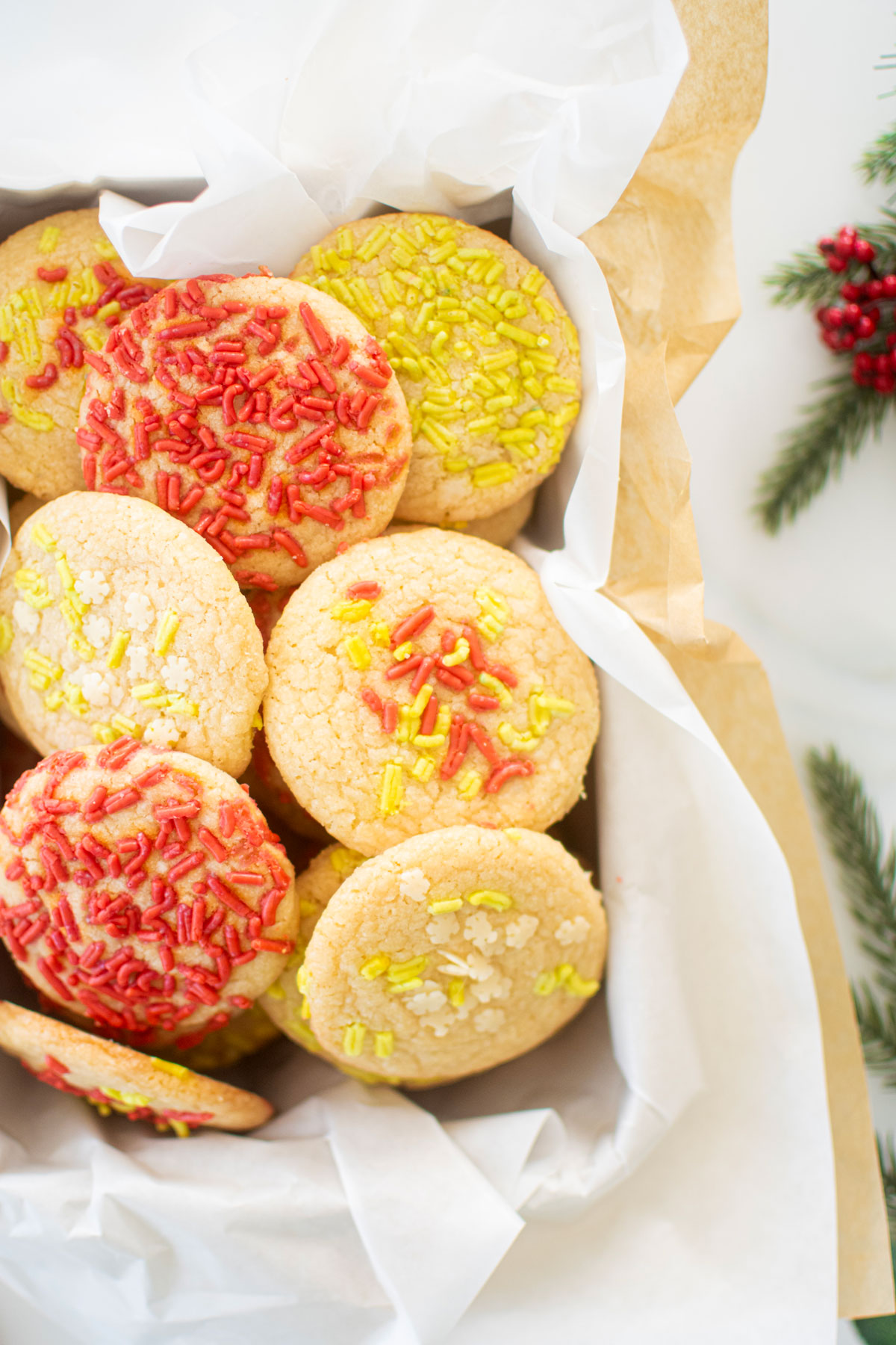 cookie tin of christmas shortbread cookies with festive sprinkles on a white marble counter.