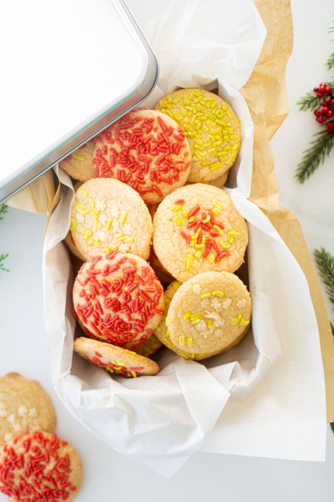 cookie tin of christmas shortbread cookies with festive sprinkles on a white marble counter.