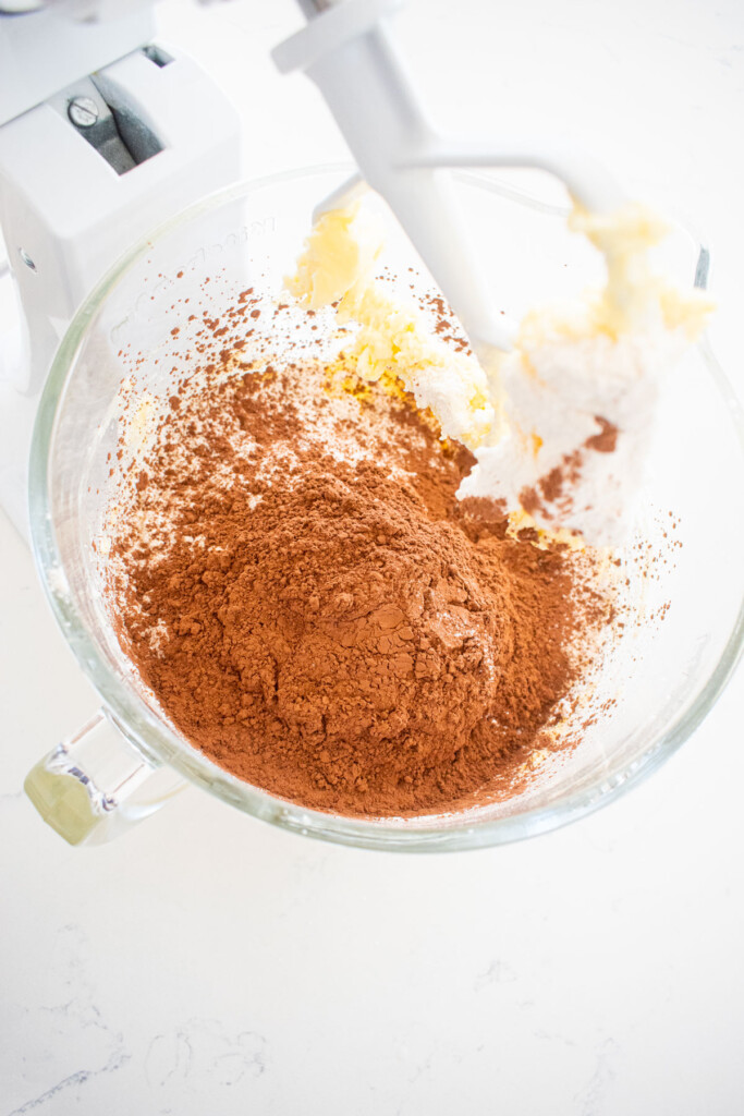 ingredients for chocolate peppermint greek butter cookies in a glass mixing bowl on a white marble counter.