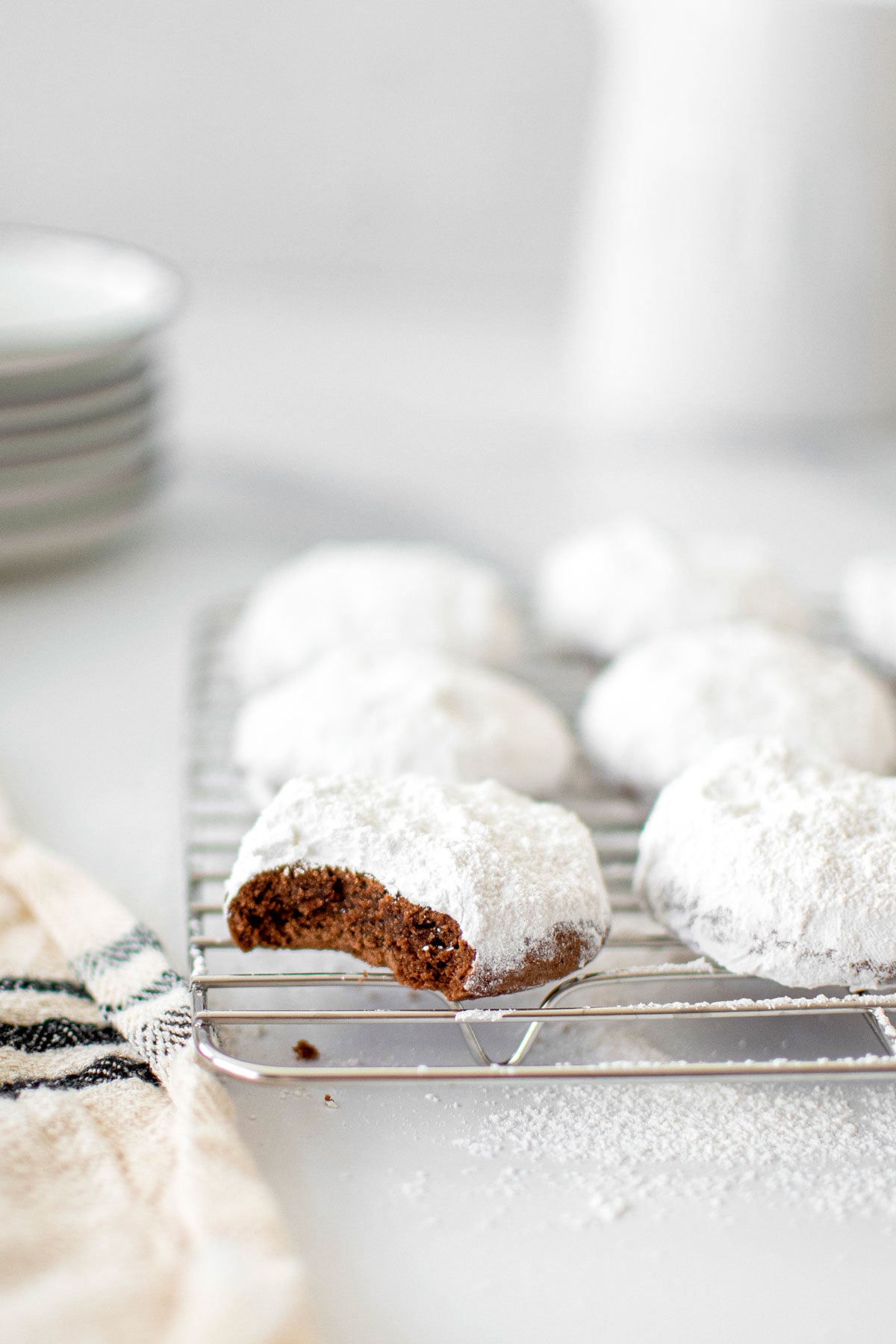 chocolate peppermint Kourambiethes (Greek Butter Cookies) on a cooling rack on a marble counter.