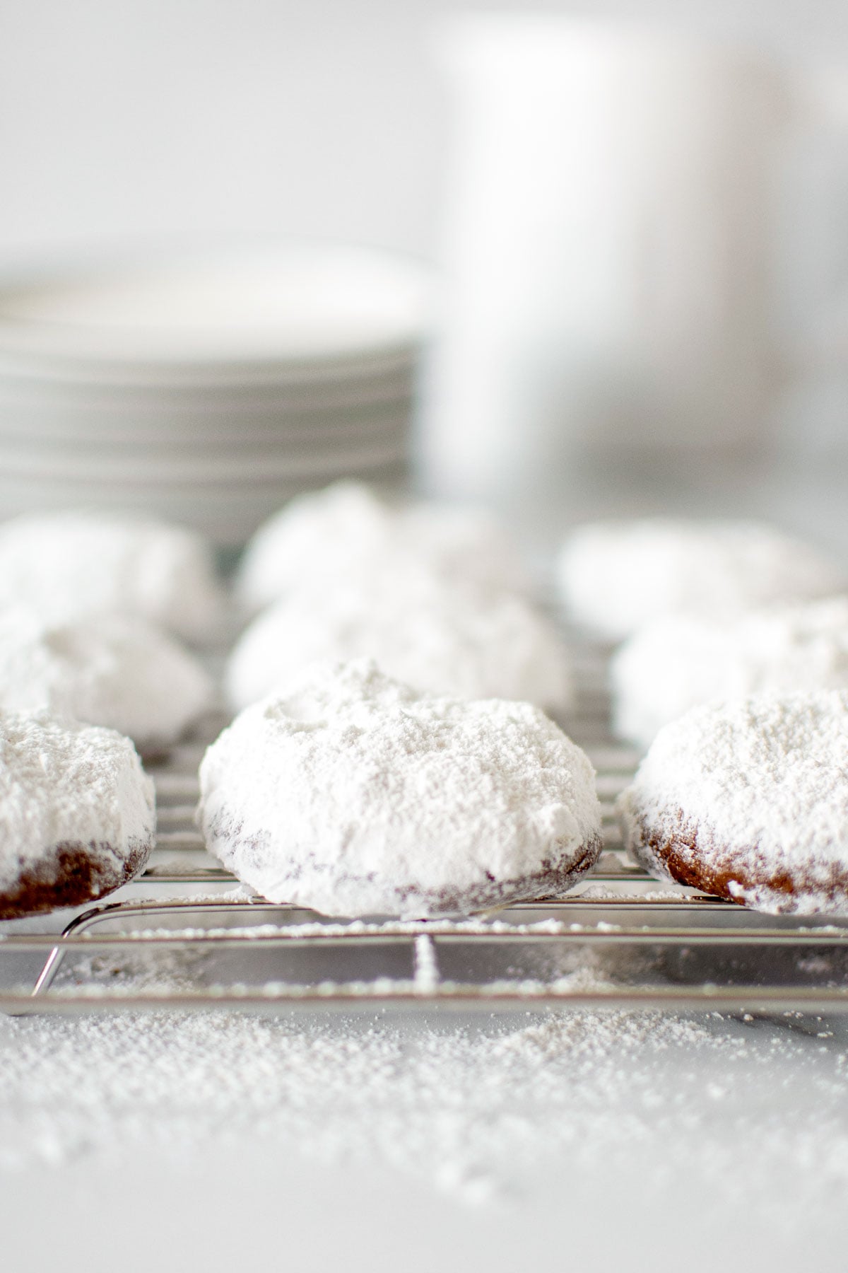 chocolate peppermint Kourambiethes (Greek Butter Cookies) on a cooling rack on a marble counter.