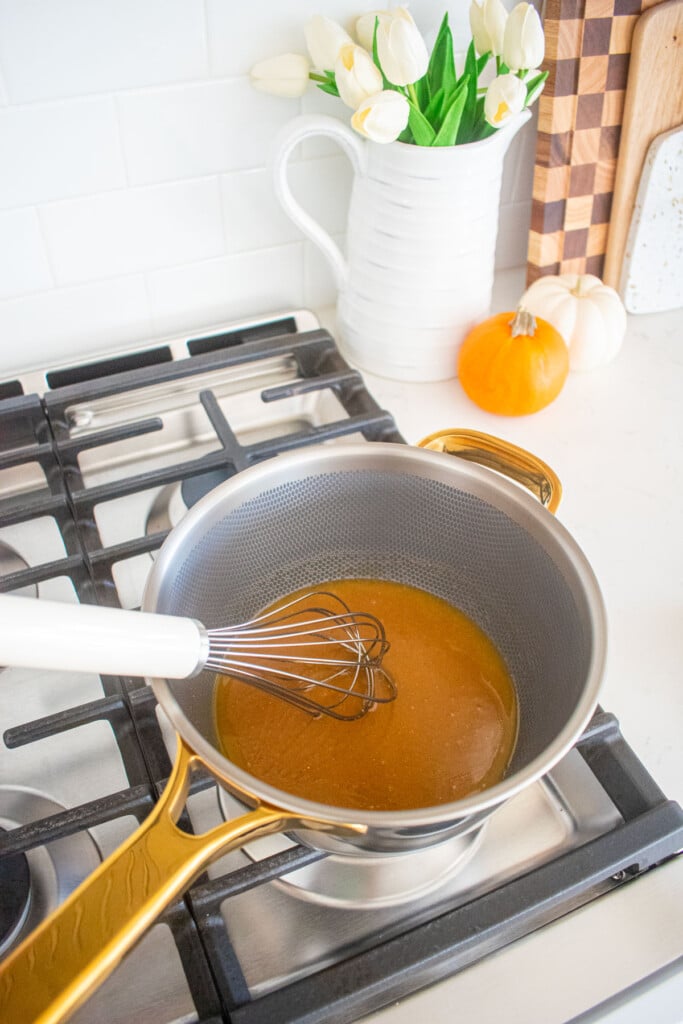wet ingredients for easy vegan peanut brittle being whisked over the stovetop in a gold and silver pot.