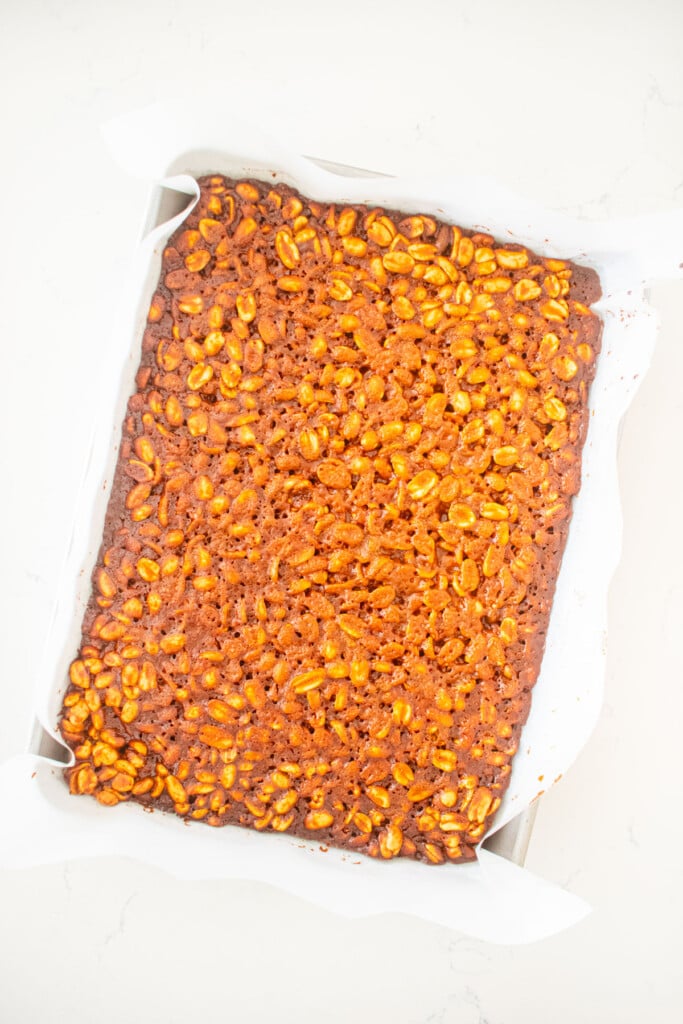 easy vegan peanut brittle baked on a quarter sheet pan on a white marble counter.