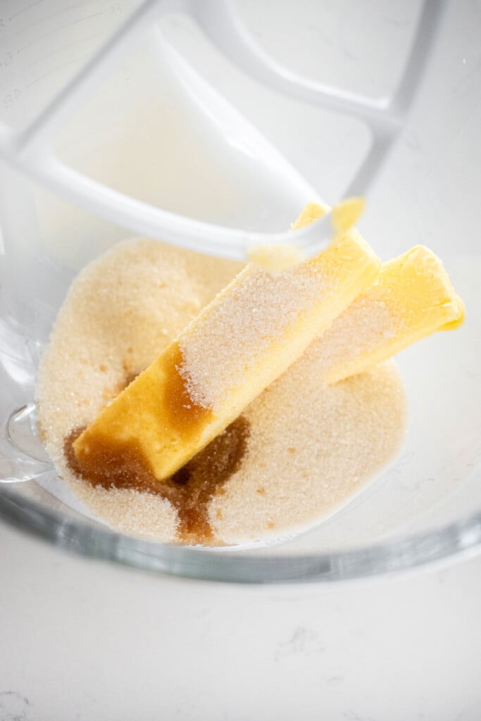 butter cane sugar and vanilla extract in a glass mixing bowl on a marble counter.