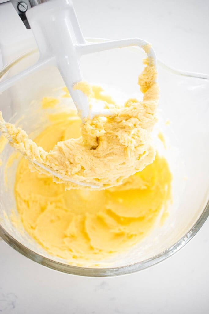 creamed butter sugar and vanilla in a glass mixing bowl on a marble counter.