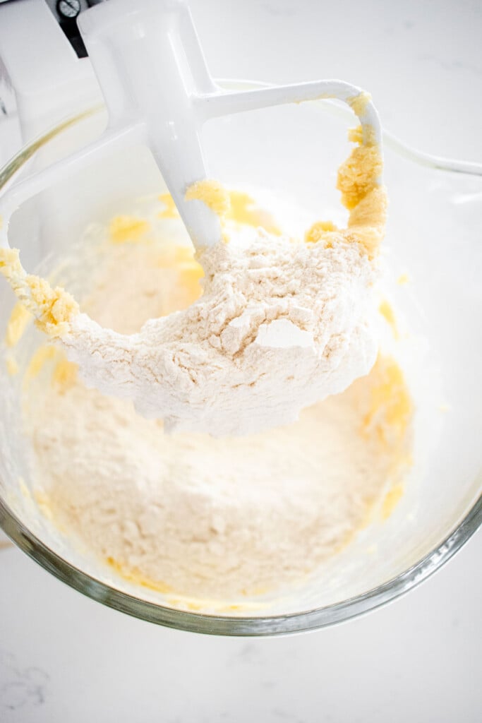 ingredients for eggless spritz cookies in a glass mixing bowl on a marble counter.