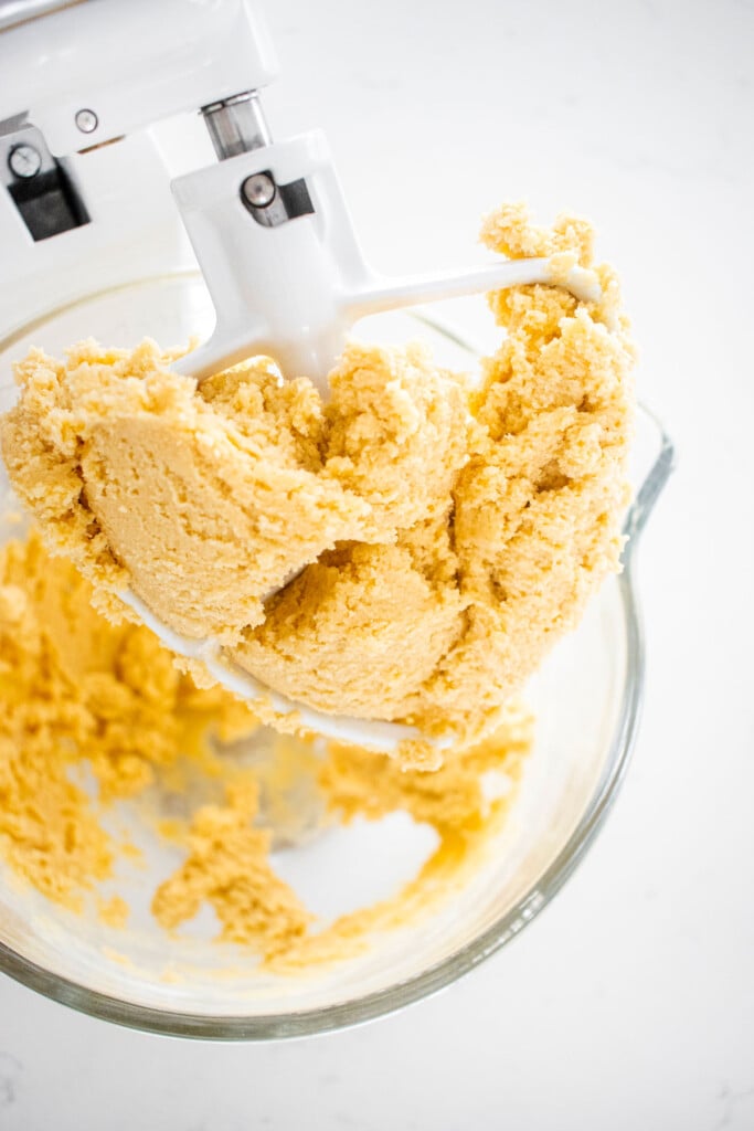 eggless spritz cookie dough in a glass mixing bowl on a marble counter.