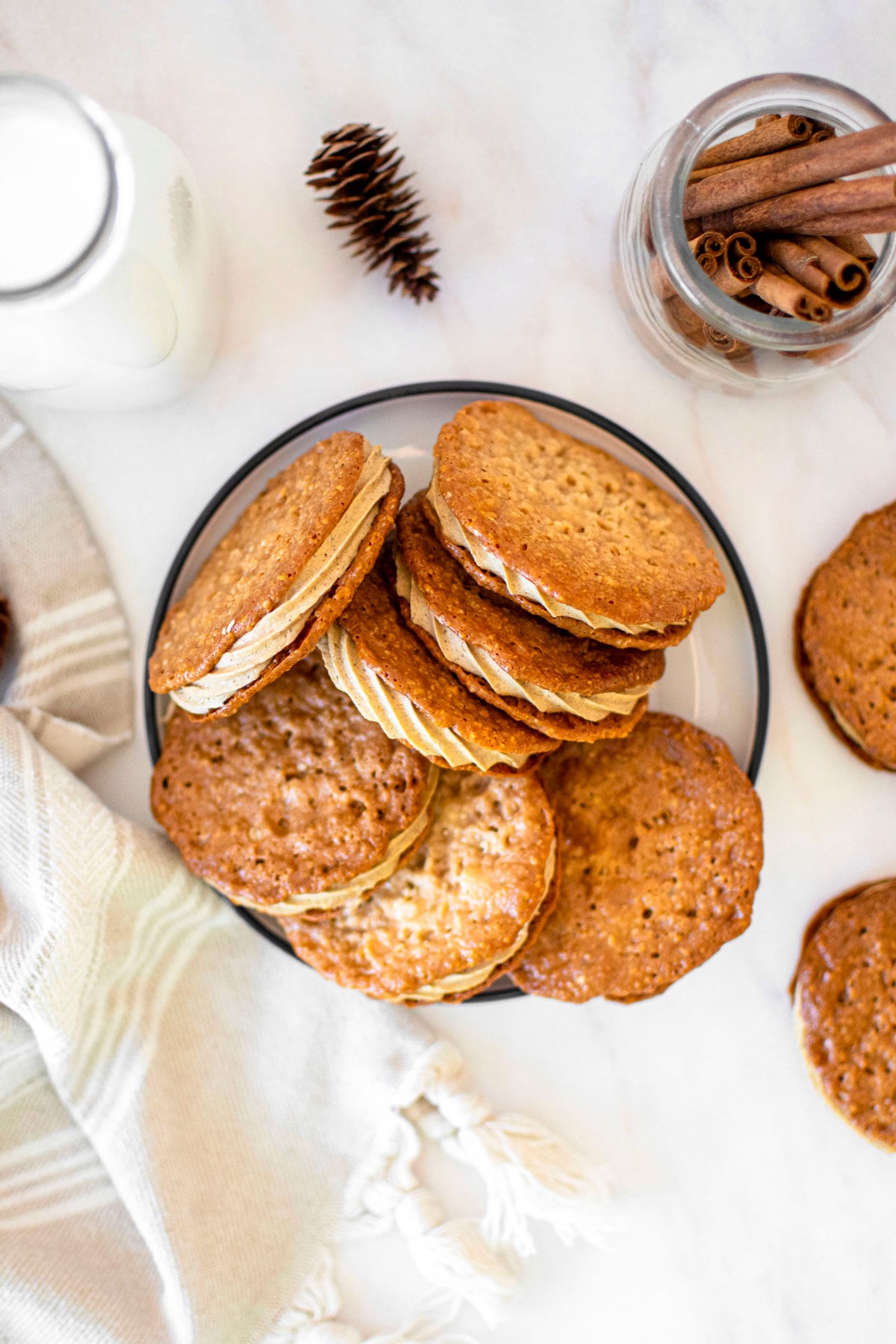 gingerbread florentine sandwich cookies on a plate on a white marble counter.