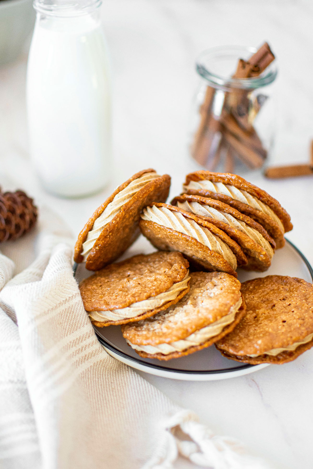 gingerbread florentine sandwich cookies on a plate on a white marble counter.
