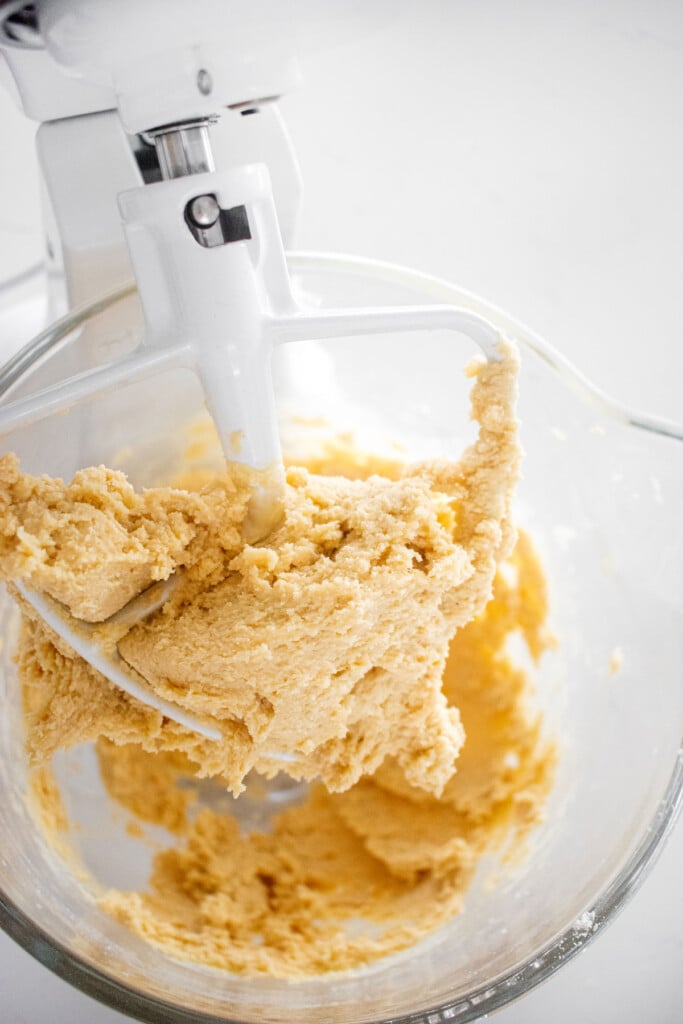 vanilla shortbread cookie dough in a glass mixing bowl on a white marble countertop.