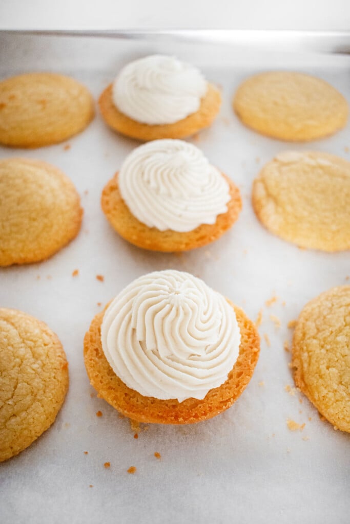 homemade vanilla oreo cookies being sandwiched together on a baking sheet.
