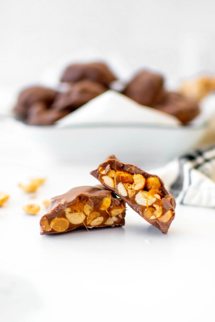 peanut turtle candy broken in half on a white marble counter.