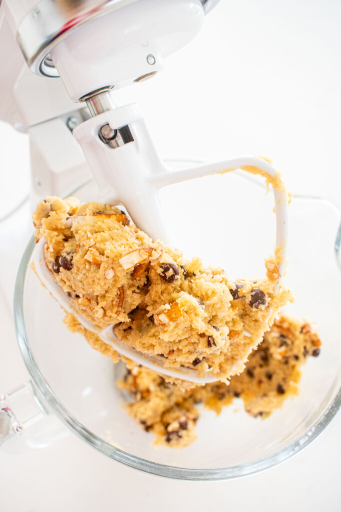 peppermint pretzel chocolate chip cookie dough in a glass mixing bowl on a white marble counter.