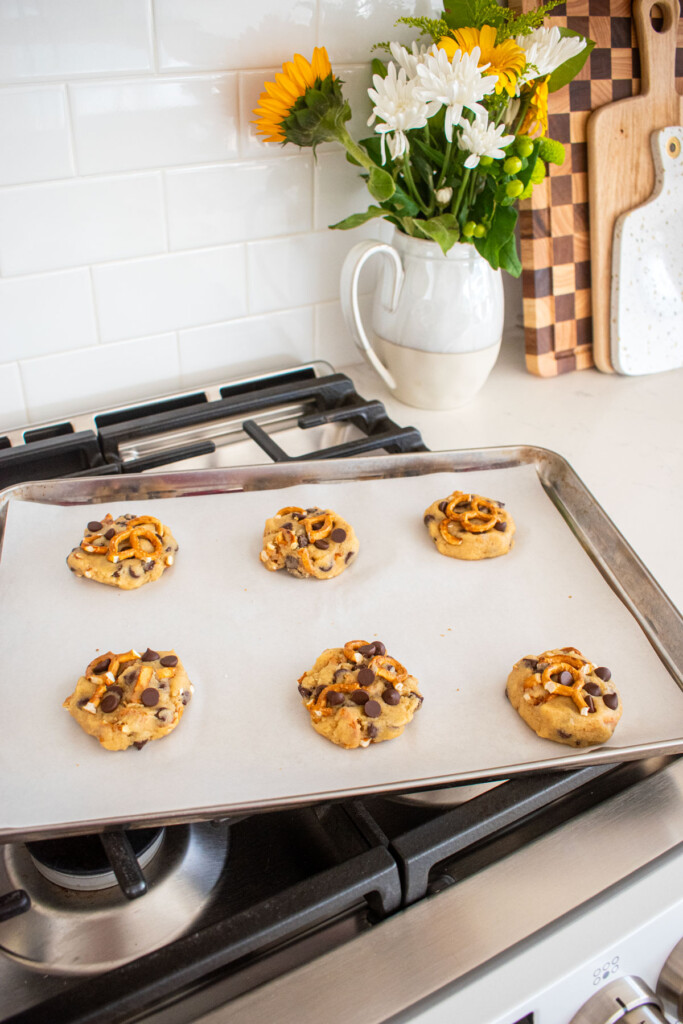 peppermint pretzel chocolate chip cookie dough balls on a baking sheet with parchment paper on an oven.
