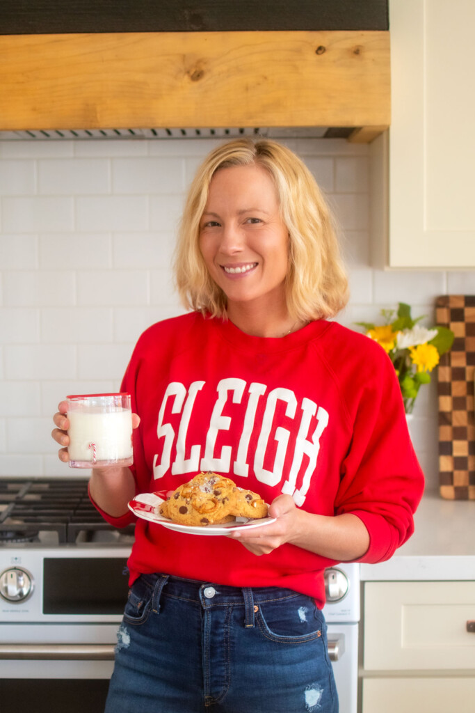 woman holding a plate of peppermint pretzel chocolate chip cookies and a glass of milk in the kitchen.