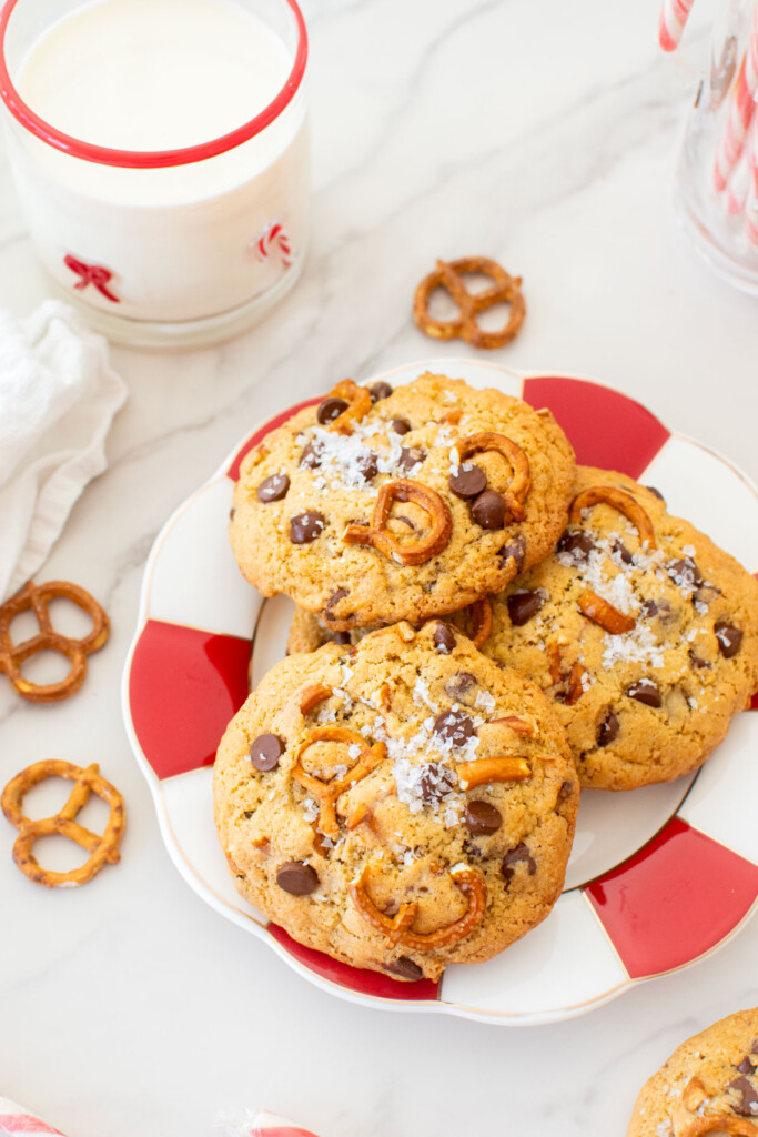 plate of peppermint pretzel chocolate chip cookies on a marble counter with a glass of milk.