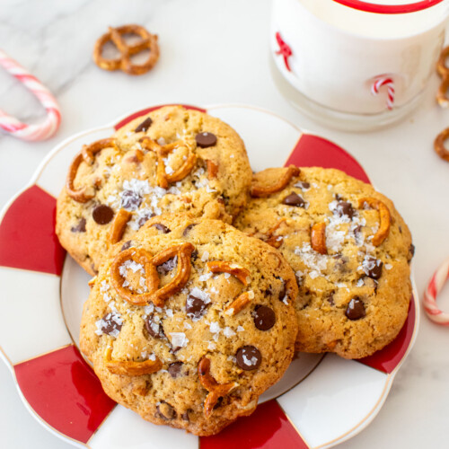 plate of peppermint pretzel chocolate chip cookies on a marble counter with a glass of milk.