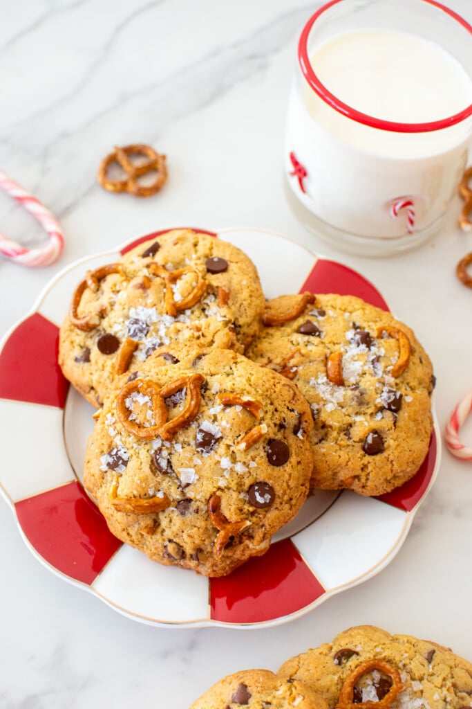 plate of peppermint pretzel chocolate chip cookies on a marble counter with a glass of milk.