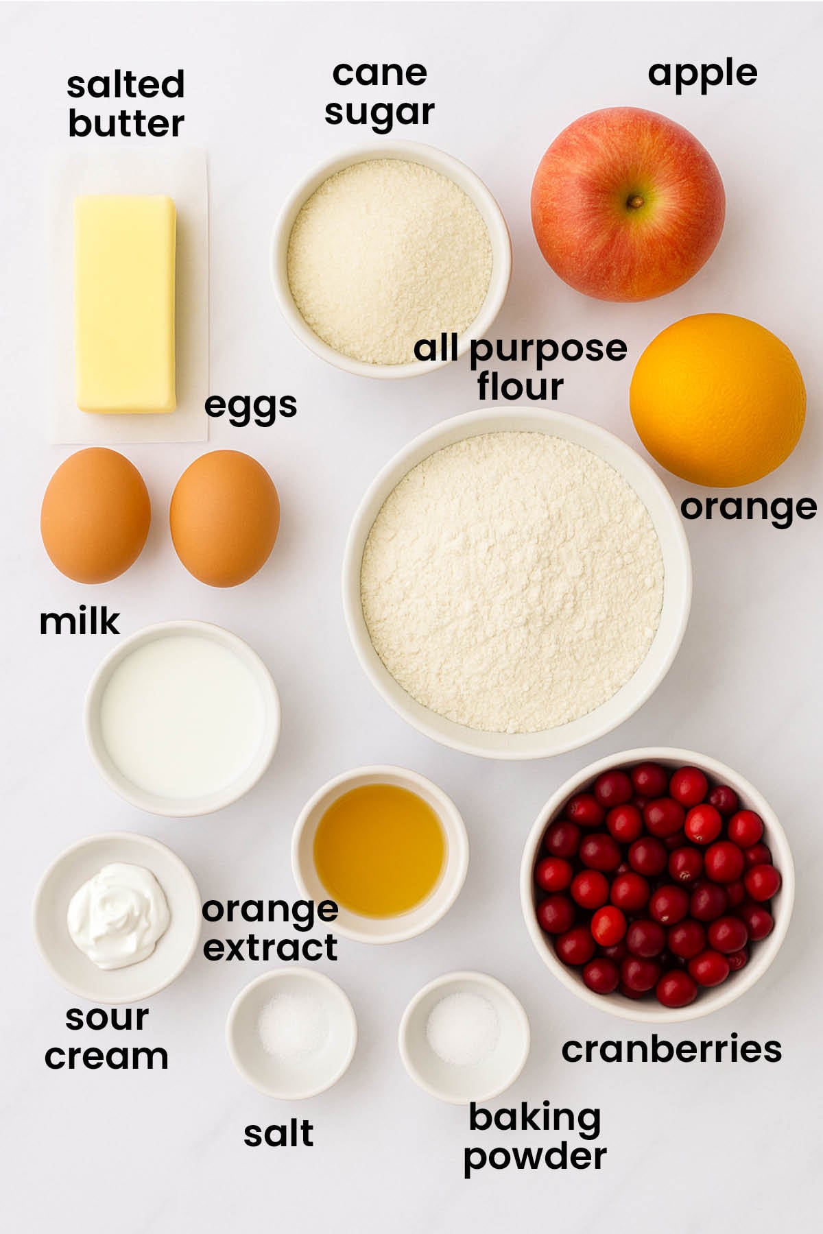 individual ingredients for cranberry orange apple bread laid out against a white background.